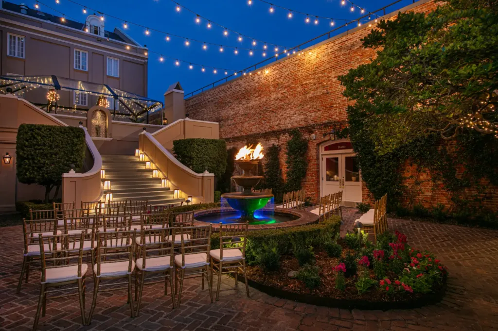 a courtyard with a fountain and seating area at night