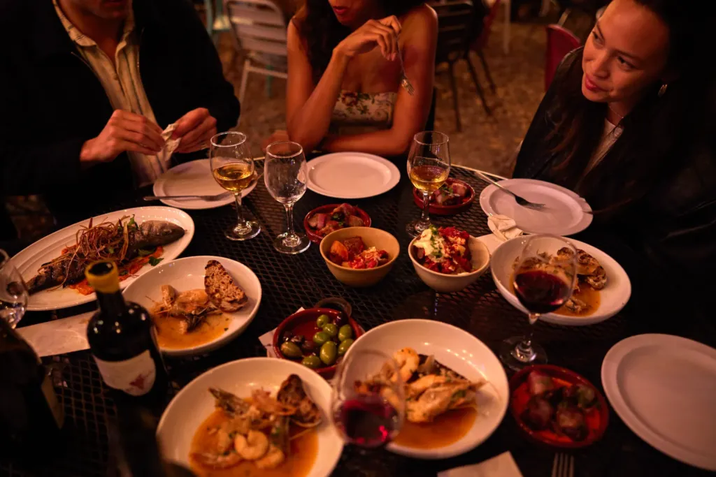 a group of people sitting around a table full of food
