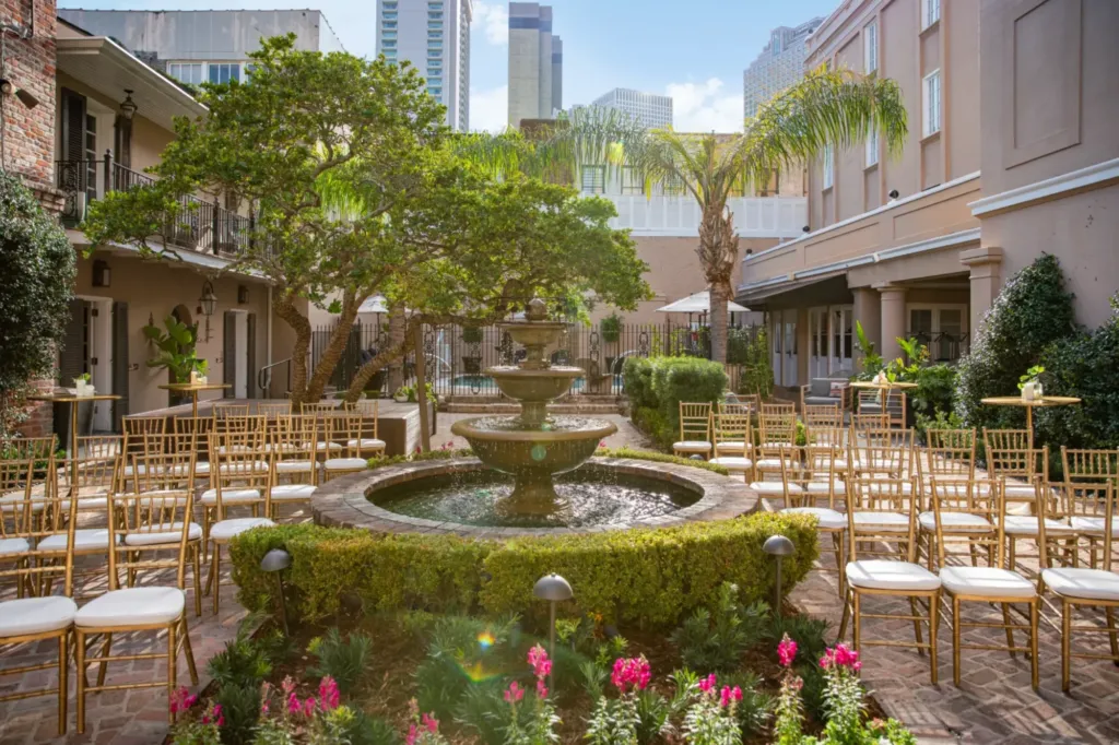 a fountain surrounded by chairs and trees in a courtyard
